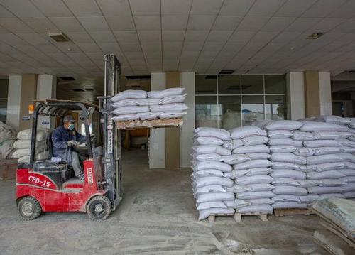 工人在贵州省毕节市黔西县岔白工业园区一家涂料厂搬运产品